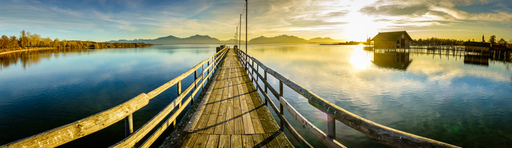 Chiemsee Abendstimmung auf einem Steg mit Blick in die Chiemgauer Alpen